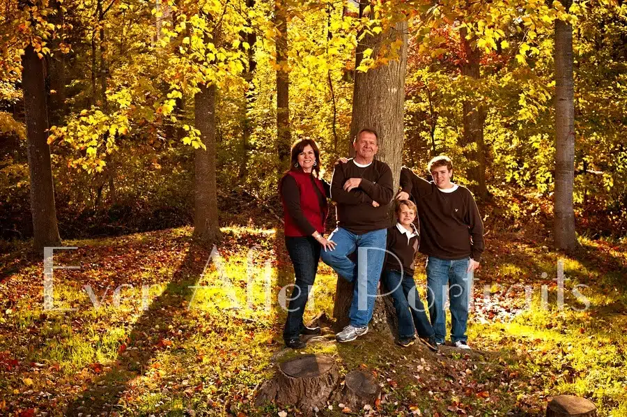 Family posing next to tree in autumn.