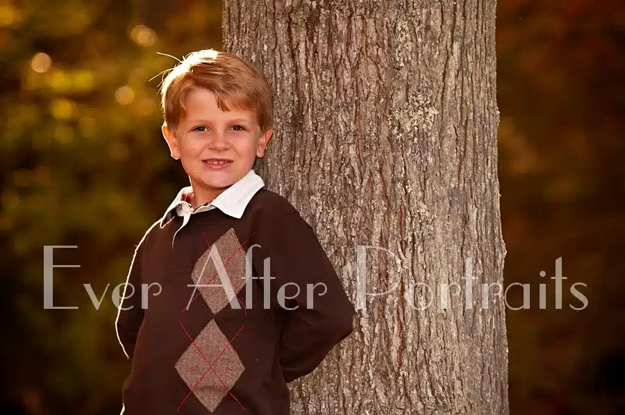 Boy standing next to tree.